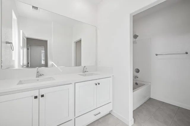 a bathroom with a double vanity sink a mirror and a bathtub