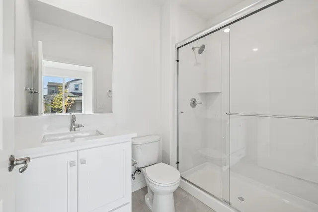 a bathroom with a shower sink vanity mirror and toilet