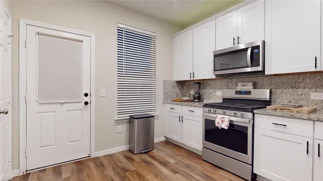 a kitchen with stainless steel appliances granite countertop a sink a stove and a wooden floors