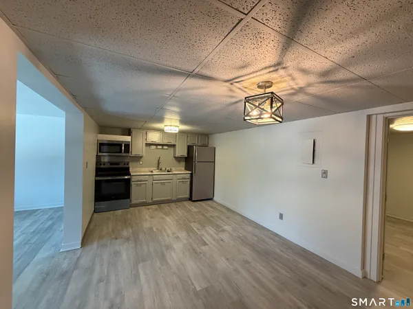 a view of a kitchen with a sink wooden cabinet and stainless steel appliances