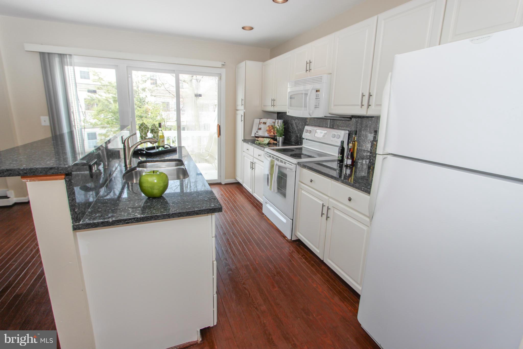 1706 Random Stone Court Reston, VA 20190 - Photo 27 of 30 a kitchen with stainless steel appliances white cabinets and wooden floor