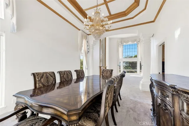 a view of a dining room with furniture a chandelier and a window