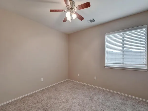 an empty room with a window and a fan