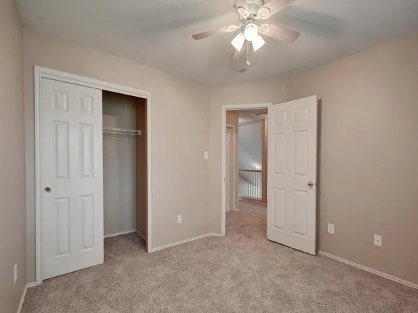 an empty room with closet and a chandelier fan
