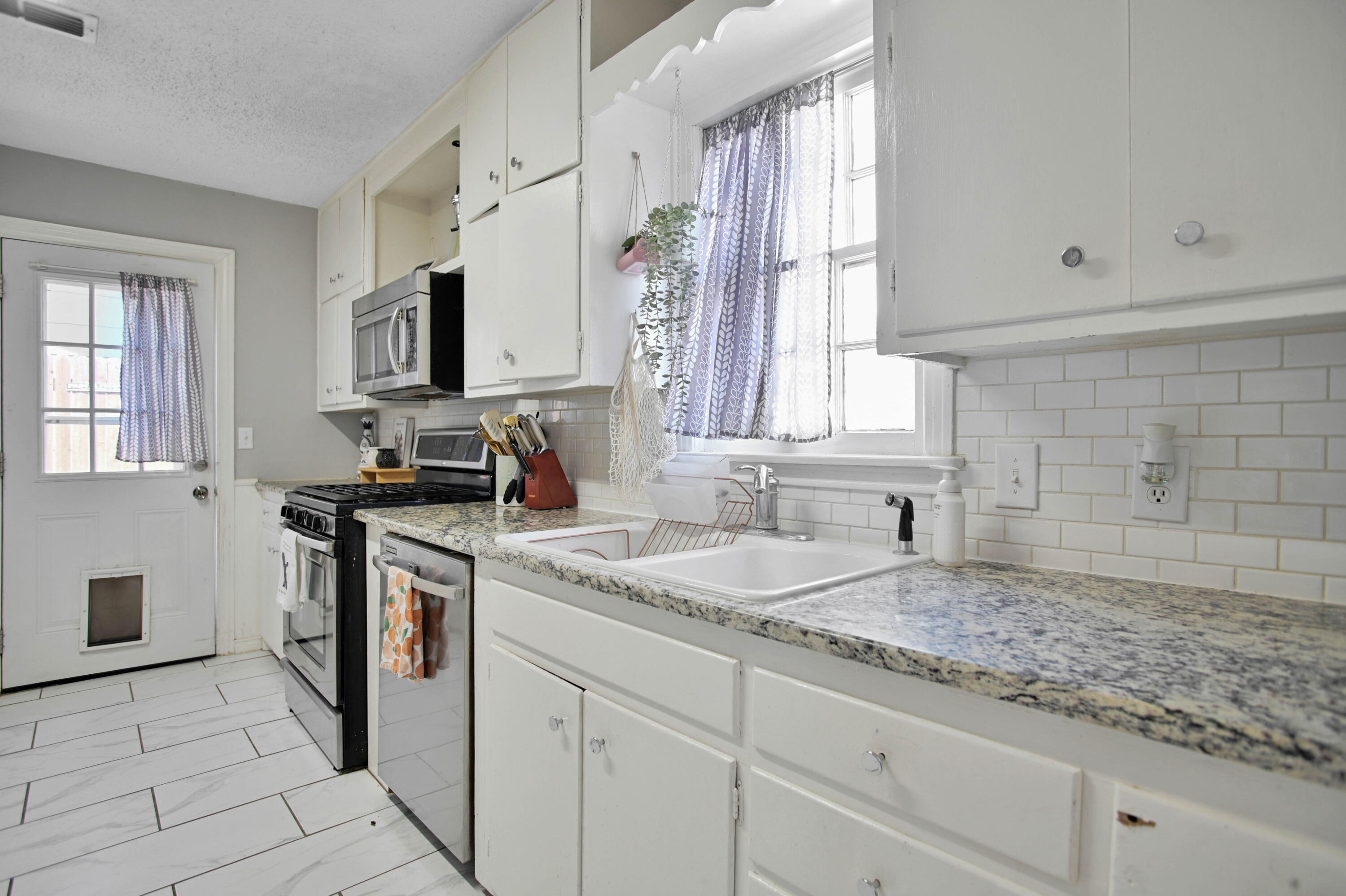 4102 32nd Street Lubbock, TX 79410 - Photo 13 of 40 a kitchen with granite countertop a sink stove and cabinets