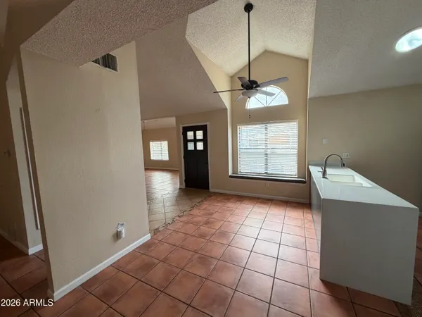 a view of an empty room with window and chandelier fan