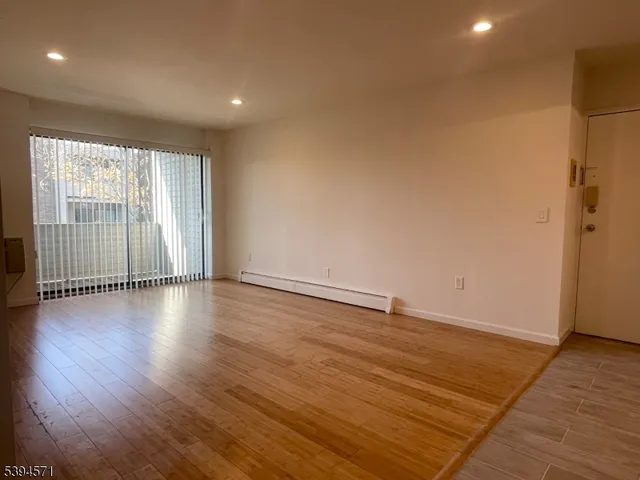 an empty room with wooden floor and windows with curtains