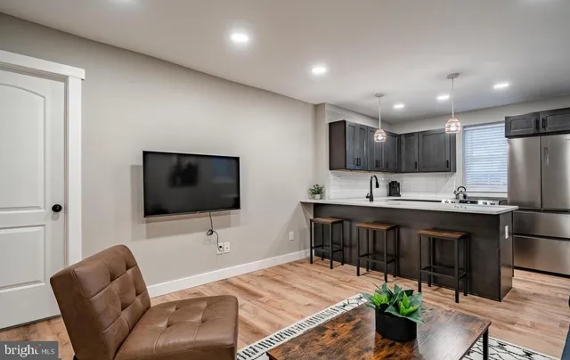 a living room with stainless steel appliances kitchen island granite countertop a couch and a flat screen tv