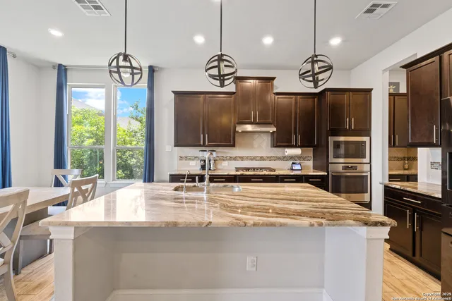 a kitchen with kitchen island granite countertop a sink a stove and a refrigerator