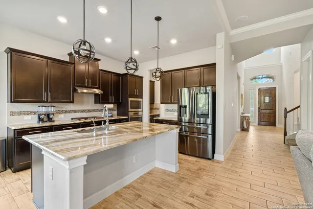 a kitchen with stainless steel appliances granite countertop a sink refrigerator and cabinets