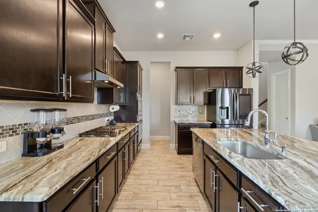 a kitchen with stainless steel appliances granite countertop a sink a stove and a refrigerator