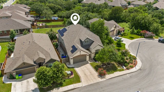an aerial view of a house with a yard and tennis court