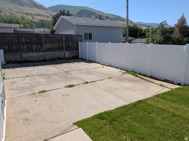 360 400 North Centerville, UT 84014 - Photo 10 of 30 Paved concrete area featuring a white privacy fence and a section of green lawn