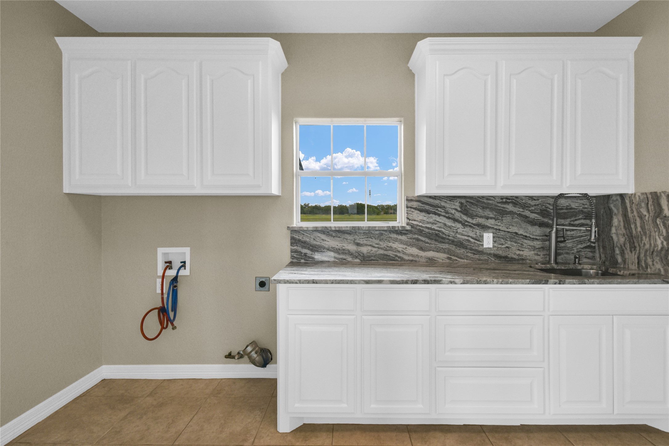 863 Bunkhouse Trail Angleton, TX 77515 - Photo 16 of 22 This photo showcases a utility room with ample white cabinetry, a striking granite countertop, and a stainless steel sink.