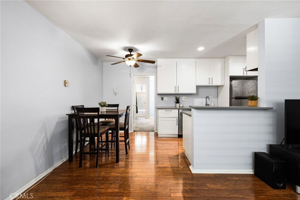 360 Gladys Avenue, Unit 2 Long Beach, CA 90814 - Photo 4 of 22 a kitchen with stainless steel appliances granite countertop a stove a refrigerator a microwave a dining table and chairs with wooden floor