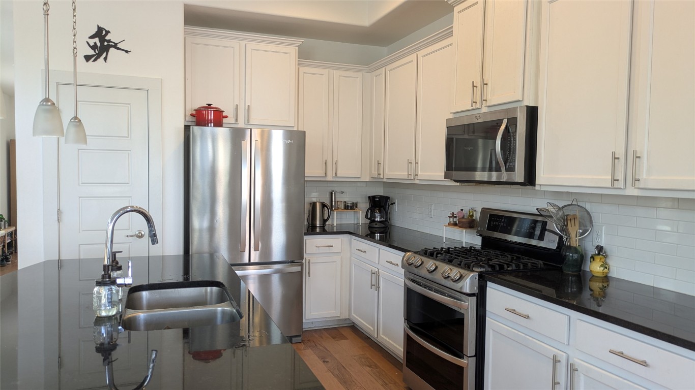 7113 Cherry Beam Path Austin, TX 78744 - Photo 5 of 24 Kitchen with stainless steel appliances, dark countertops, and tasteful backsplash