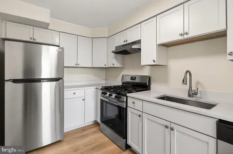 a kitchen with cabinets appliances and wooden floor