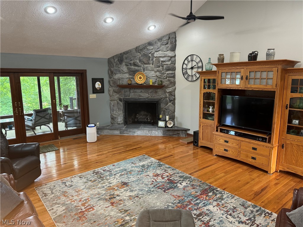 382 Riverview Acres Road Washington, WV 26181 - Photo 2 of 24 Living room with light hardwood / wood-style flooring, vaulted ceiling, a fireplace, a textured ceiling, and ceiling fan