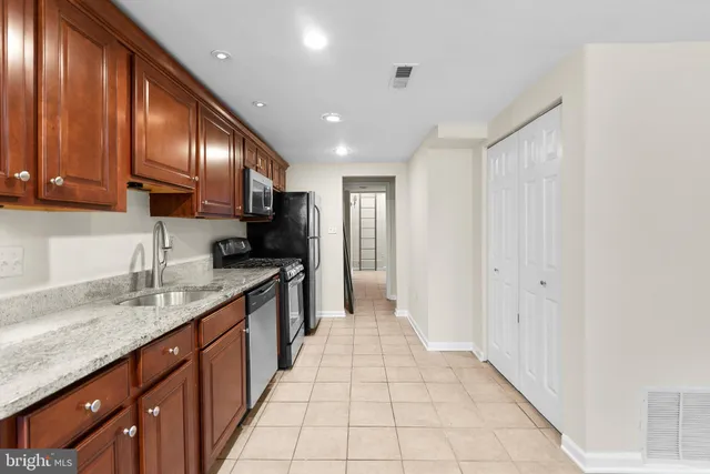 a large kitchen with granite countertop a sink dishwasher stove and cabinets