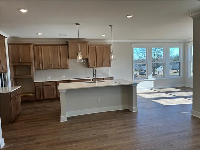 a view of kitchen with kitchen island a sink wooden floor and a living room view