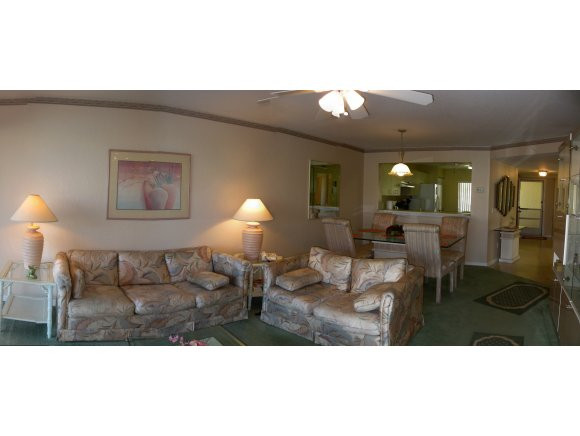 409 Gabriel Circle, Unit 7 Naples, FL 34104 - Photo 7 of 18 a living room with furniture a lamp and a large mirror