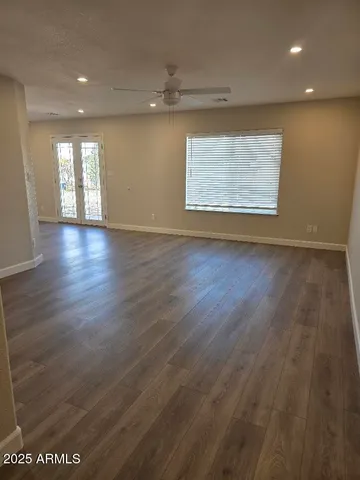 an empty room with wooden floor cabinet and windows