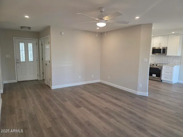an empty room with wooden floor cabinet and windows