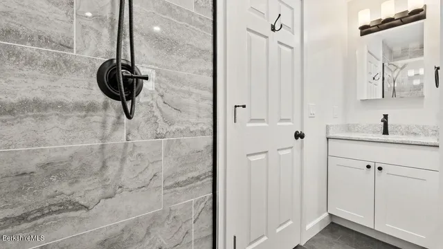 a bathroom with a granite countertop shower a sink and a mirror