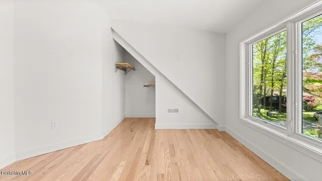 a view of an empty room with wooden floor and fan