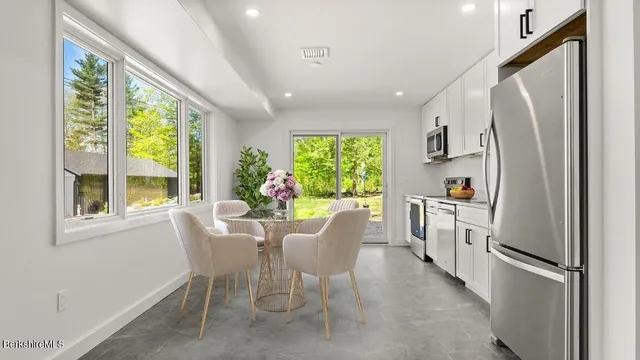 a dining room with stainless steel appliances granite countertop a refrigerator and a window