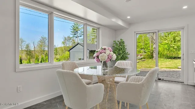 a dining room with furniture large windows and wooden floor