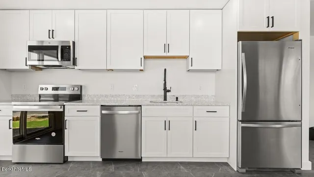 a kitchen with stainless steel appliances white cabinets and a refrigerator