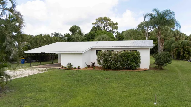 a view of a white house with a yard and potted plants