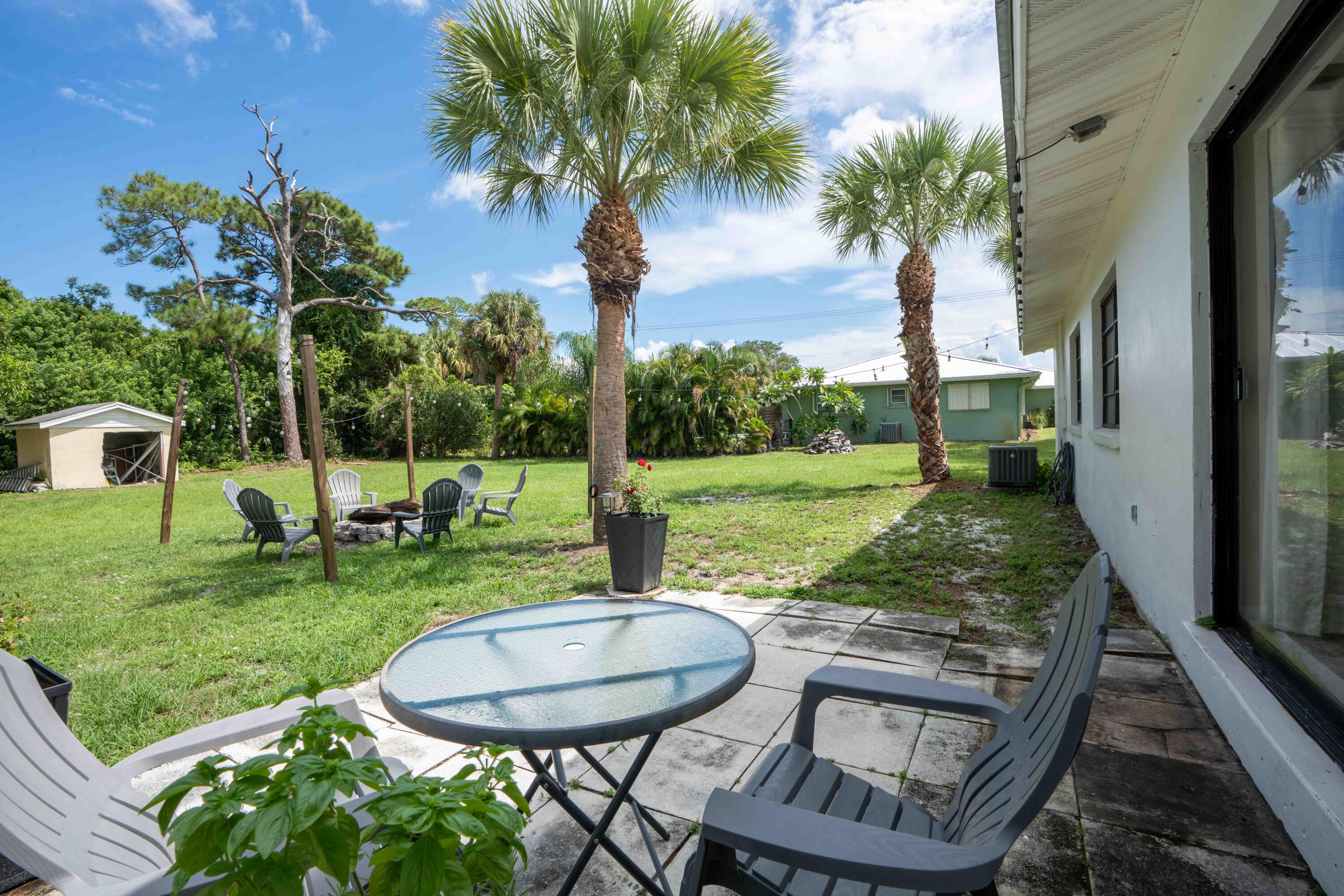 1849 Northwest Pine Tree Way Stuart, FL 34994 - Photo 17 of 29 a view of a backyard with table and chairs potted plants and palm tree
