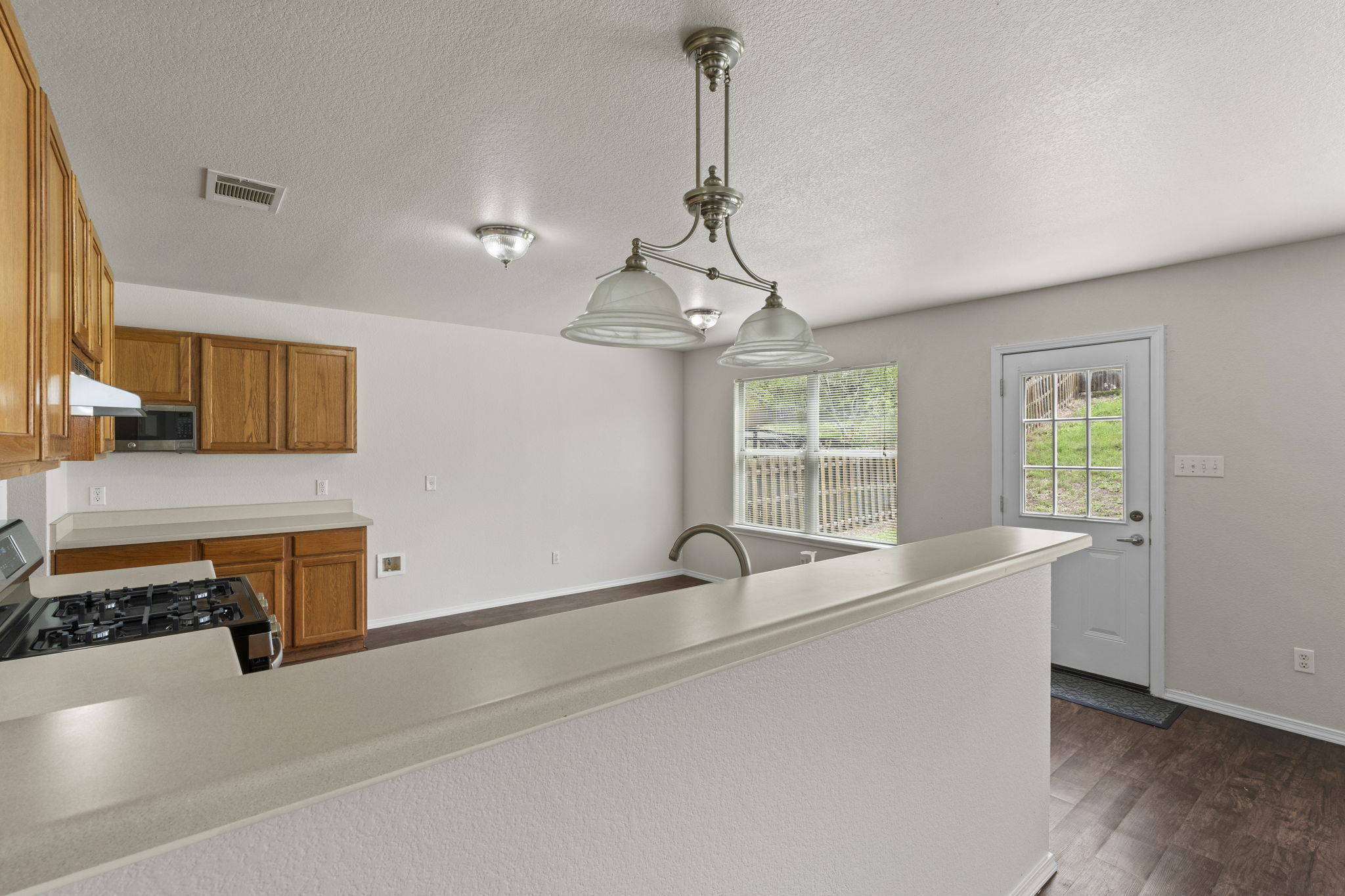 208 Dandelion Loop Kyle, TX 78640 - Photo 13 of 39 Kitchen featuring wood cabinetry, a built-in microwave, and a gas range with dining area