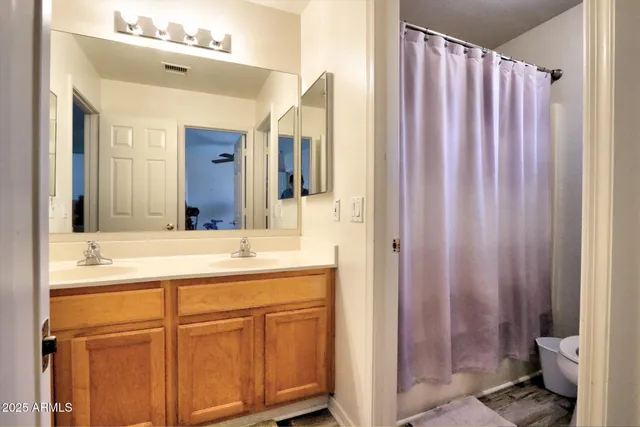 a en suite bathroom with a granite countertop sink and a mirror