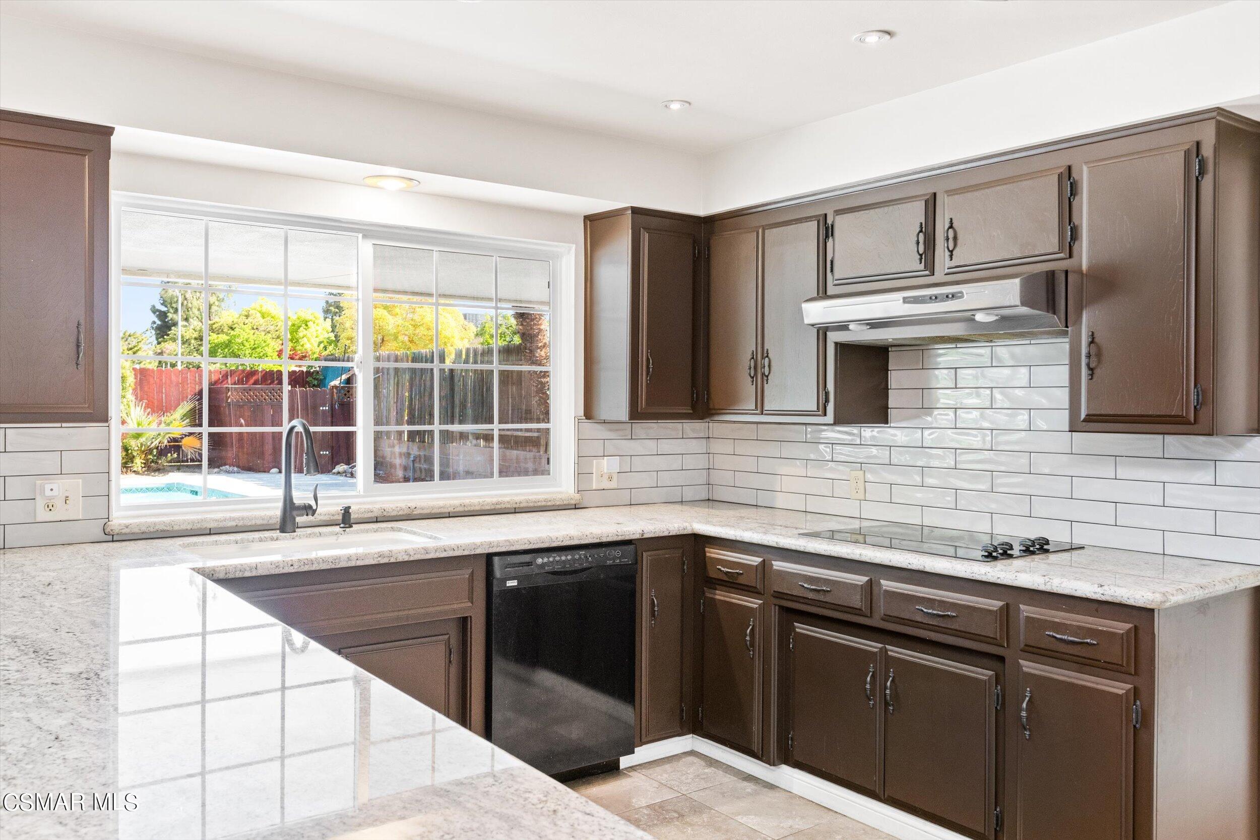 3512 Crest Drive Bakersfield, CA 93306 - Photo 23 of 40 a kitchen with stainless steel appliances kitchen island granite countertop a sink and dishwasher a stove top oven with wooden floor