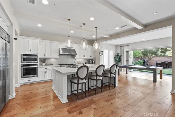 a kitchen with stainless steel appliances granite countertop a stove a sink a refrigerator a center island a table and chairs