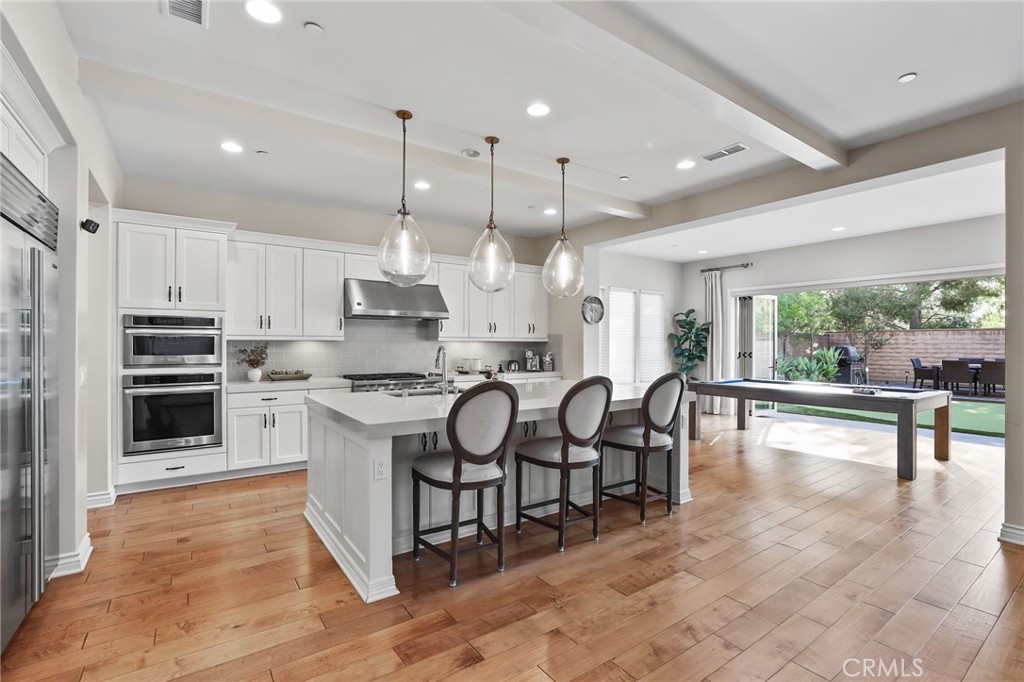 10 Shadybend Irvine, CA 92602 - Photo 12 of 70 a kitchen with stainless steel appliances kitchen island granite countertop a stove a sink a oven and a dining table with wooden floor