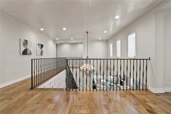 a view of a hallway with wooden floor and a bathroom