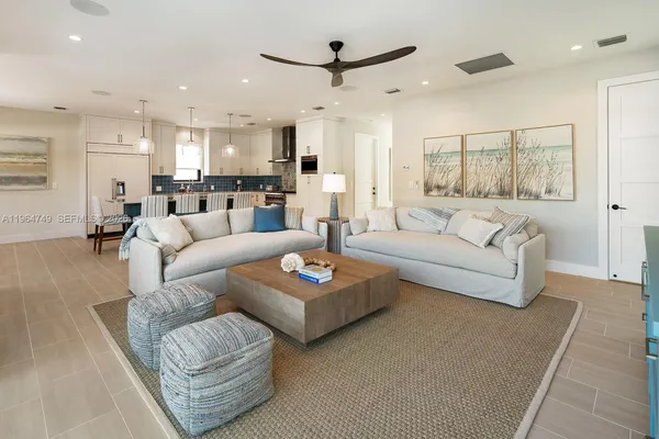 a living room with furniture kitchen view and a chandelier