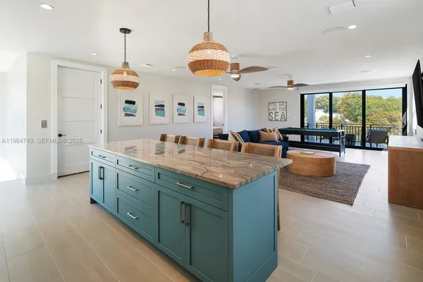 a living room with granite countertop kitchen island stainless steel appliances furniture and a chandelier
