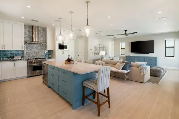 a large living room with stainless steel appliances granite countertop couches a flat screen tv with kitchen view