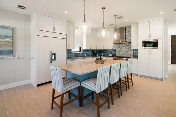 a kitchen with stainless steel appliances granite countertop a stove a refrigerator a kitchen island a sink and a refrigerator
