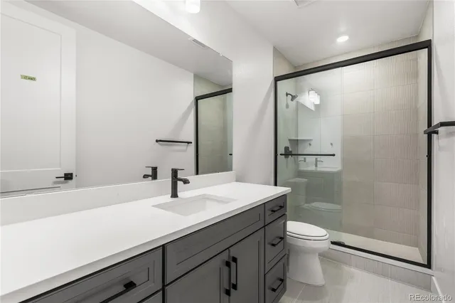 a bathroom with a sink a toilet a mirror and shower