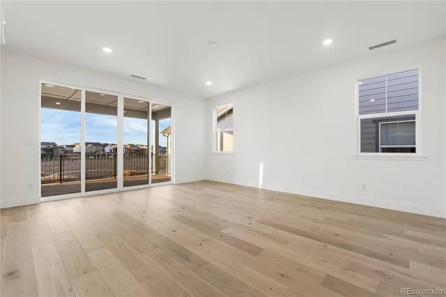 a view of an empty room with wooden floor and windows