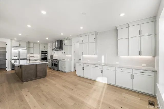 a large kitchen with kitchen island a sink white cabinets and stainless steel appliances