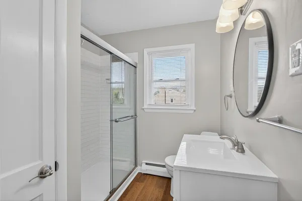a bathroom with a toilet a sink a mirror and a window