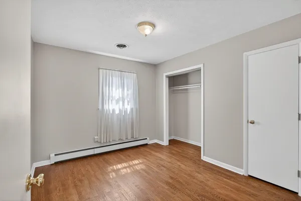 an empty room with wooden floor and fireplace