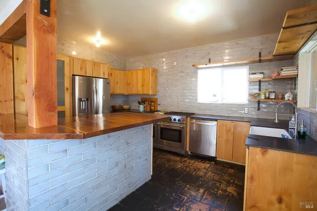 a kitchen with stainless steel appliances granite countertop a sink a stove and a refrigerator